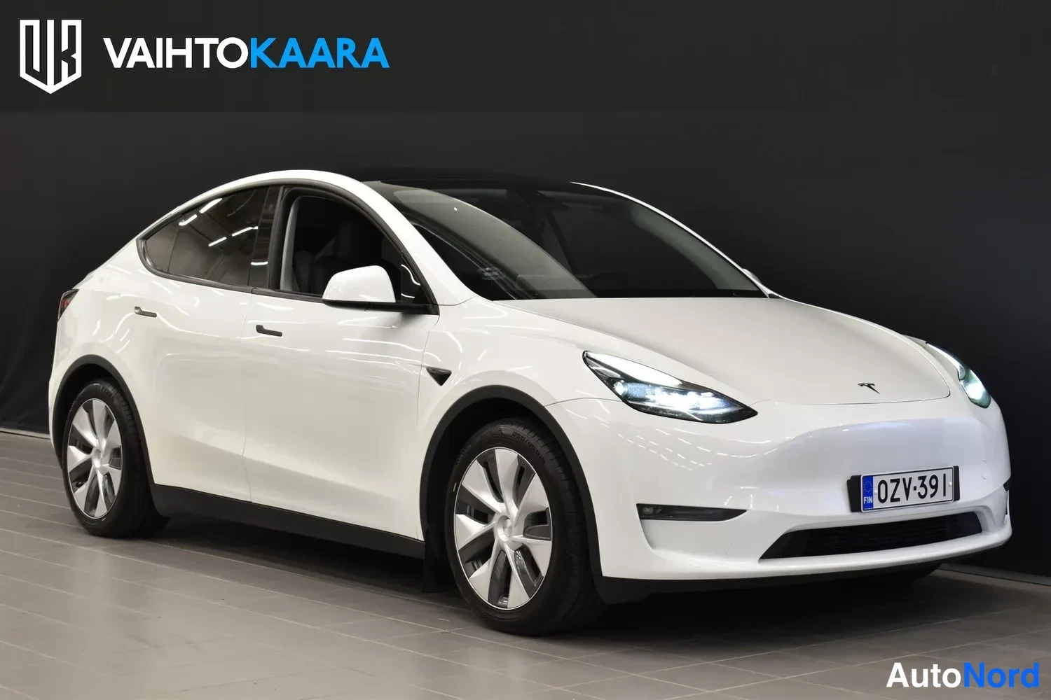 Etuviisto, nokka oikealle: Valkoisen Tesla Model Y:n etukulma, keulä kuvassa oikealla, rekisterikilpi.