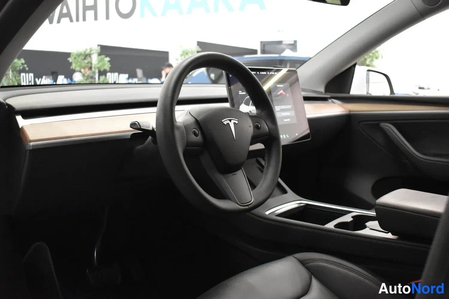 Muu: Tesla Model Y:n ohjaamo: T-logolla varustettu ohjauspyörä ja keskikonsolin suuri näyttö.