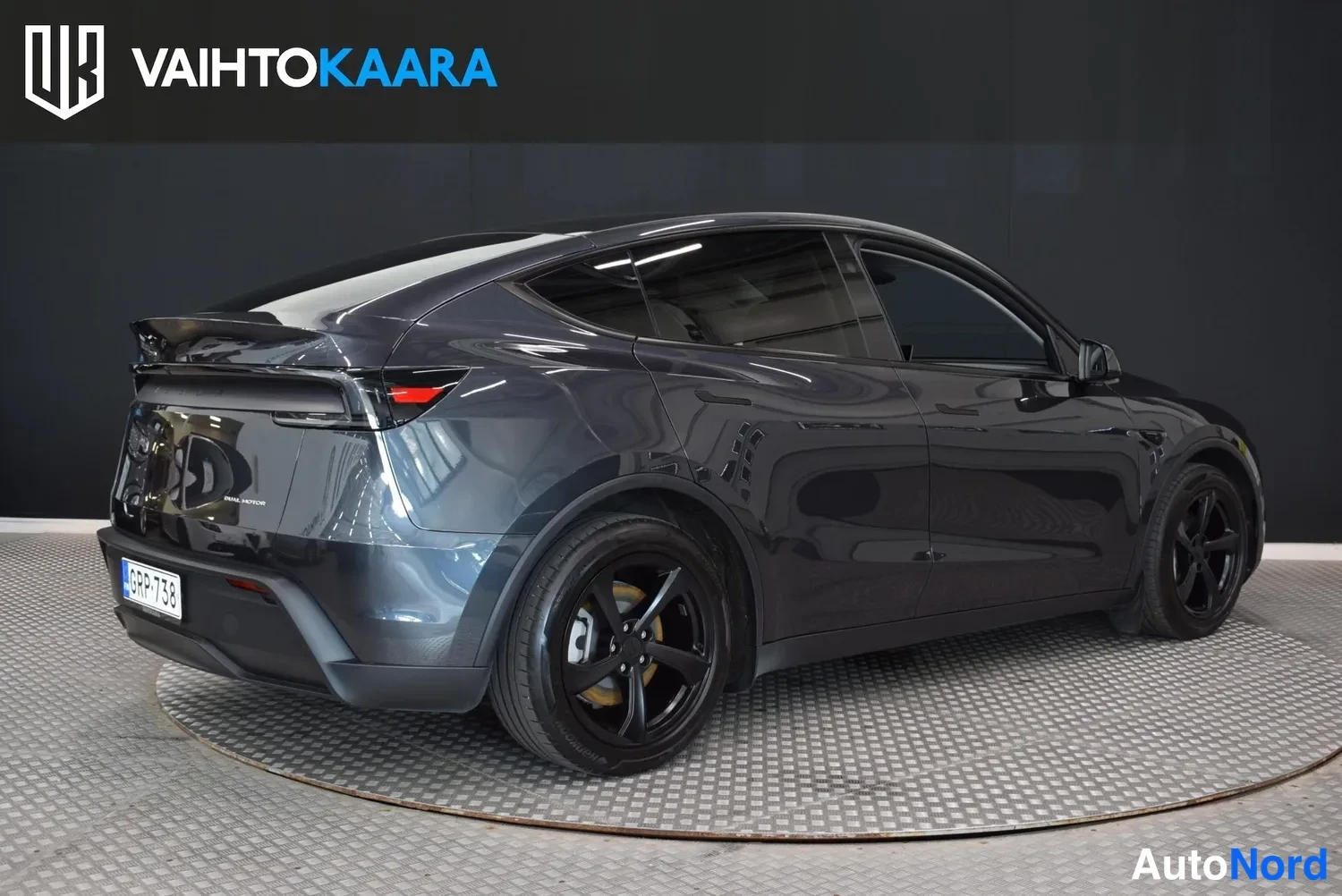 Takaviisto: Tummanharmaa Tesla Model Y takavasemmasta kulmasta, rekisteritunnus.