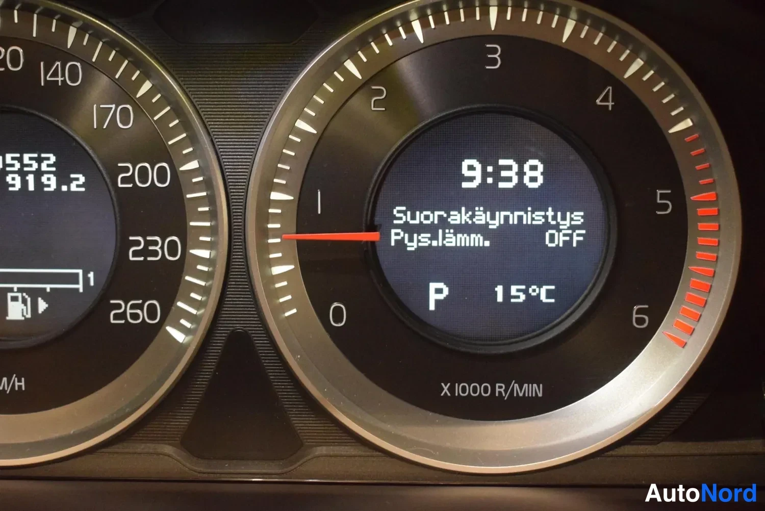 Yksityiskohta: Tacho- ja nopeusmittarit; näyttö näyttää kellonajan 9:38, teksti Suorakäynnistys / Pys.lämm. OFF, vaihteen P ja ulkolämpötilan 15 °C.