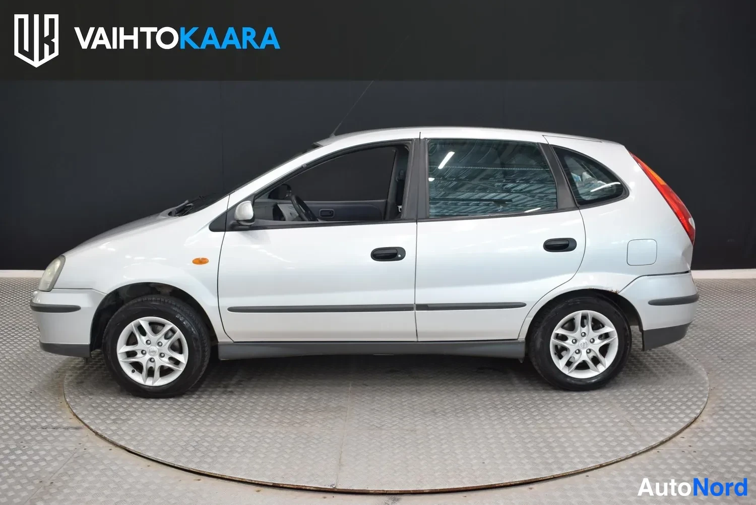 Sivulta: Sivukuva hopeanvärisestä Nissan Almera Tino -henkilöautosta oikealta puolelta.