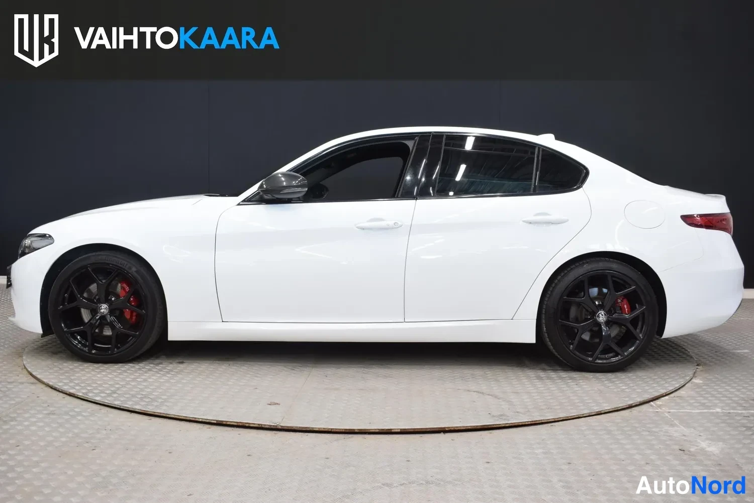 Sivulta: Valkoisen Alfa Romeo Giulia -sedanin sivuprofiili, mustat vanteet punaisilla jarrustimilla.
