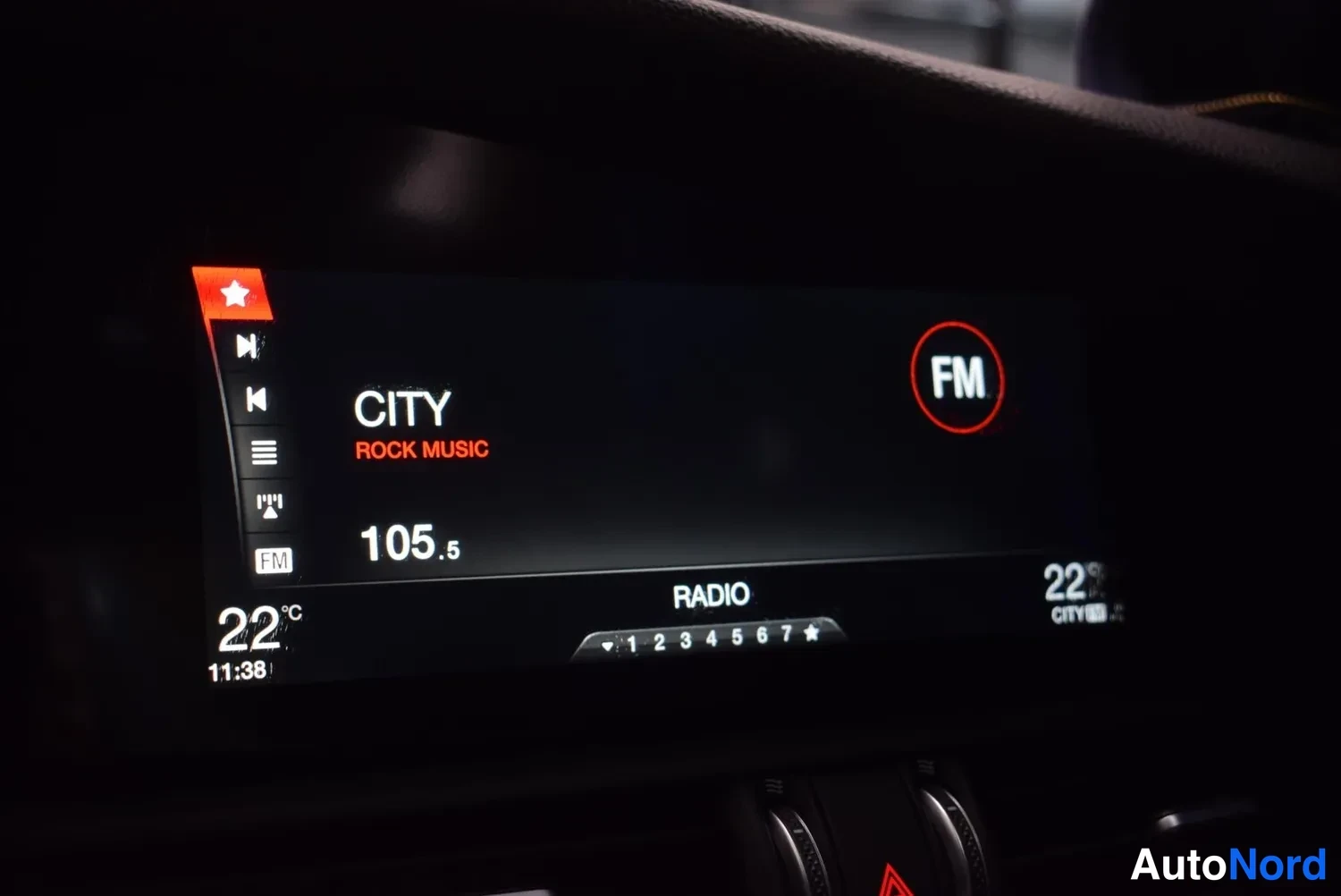 Yksityiskohta: Takometrin infotainment-näyttö radiotilassa: FM-kanava CITY ROCK MUSIC taajuudella 105.5, lämpötila 22 °C ja kello 11:38.