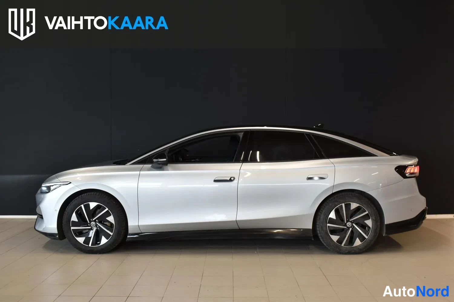 Sivulta: Volkswagen ID.7 -sedanin sivuprofiili vasemmalta sisätiloissa, hopea kori ja tummat ikkunat.