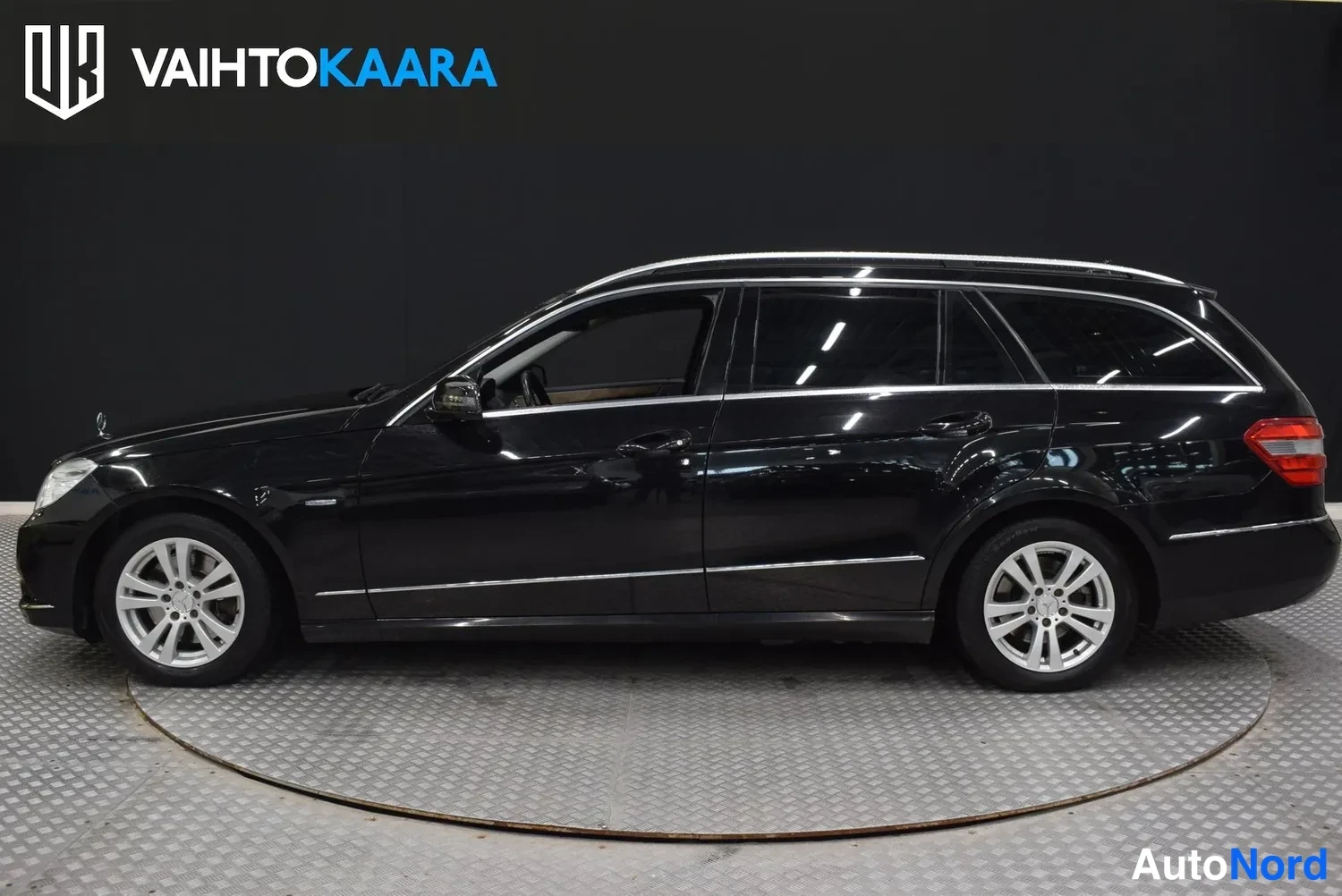 Sivulta: Musta Mercedes-Benz farmarivaihtoehto vasemmalta sivulta nähtynä, pyörät ja haketuskatto-oven linjat näkyvät.