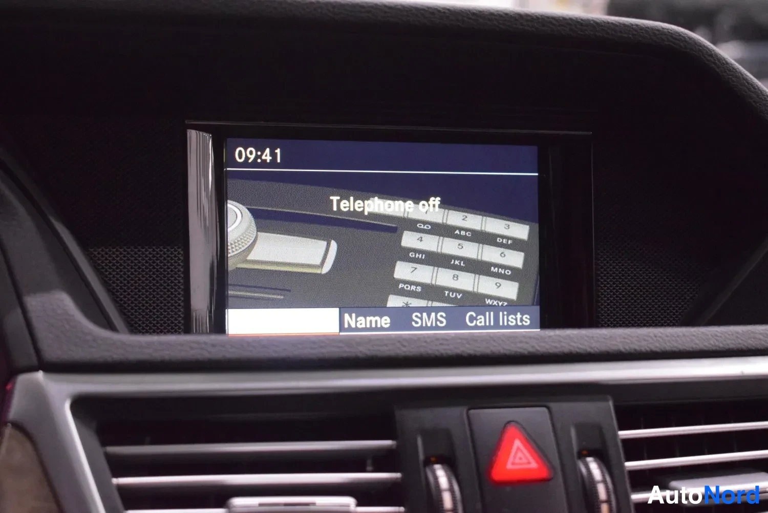 Yksityiskohta: Kojelaudan näytössä teksti Telephone off ja numeronäppäimistö, aikana 09:41; alapuolella valikot Name, SMS ja Call lists sekä punainen varoituskohtalo-kolmio.