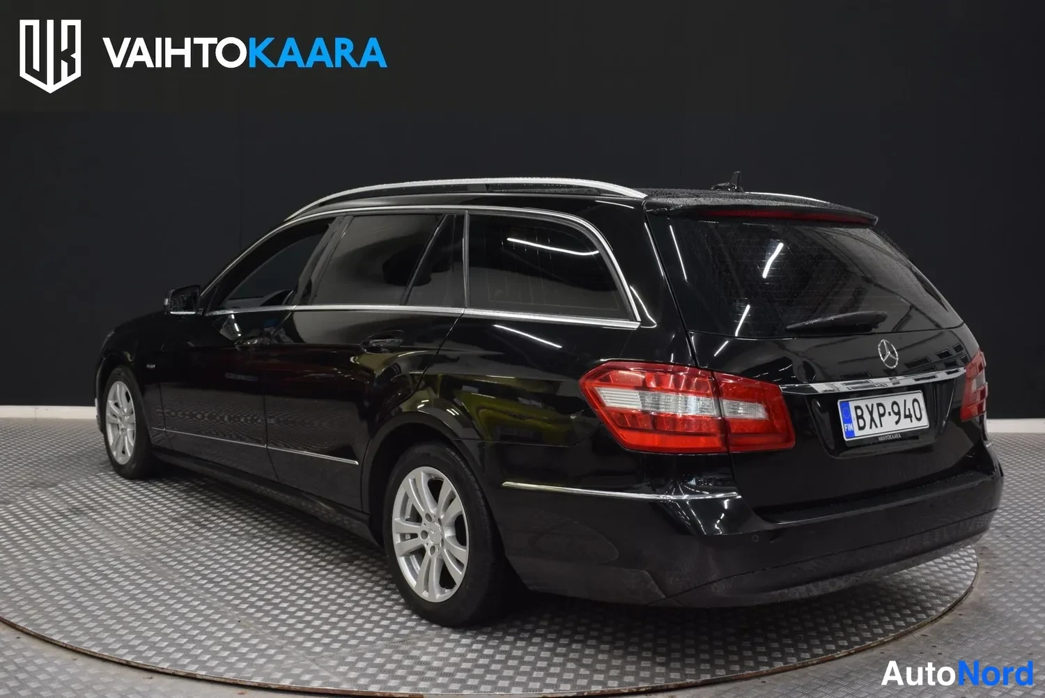 Takaviisto: Musta Mercedes-Benz farmariauto takaa kolmen neljäsosan kulmasta, peräpeilin takana rekisterikilpi.