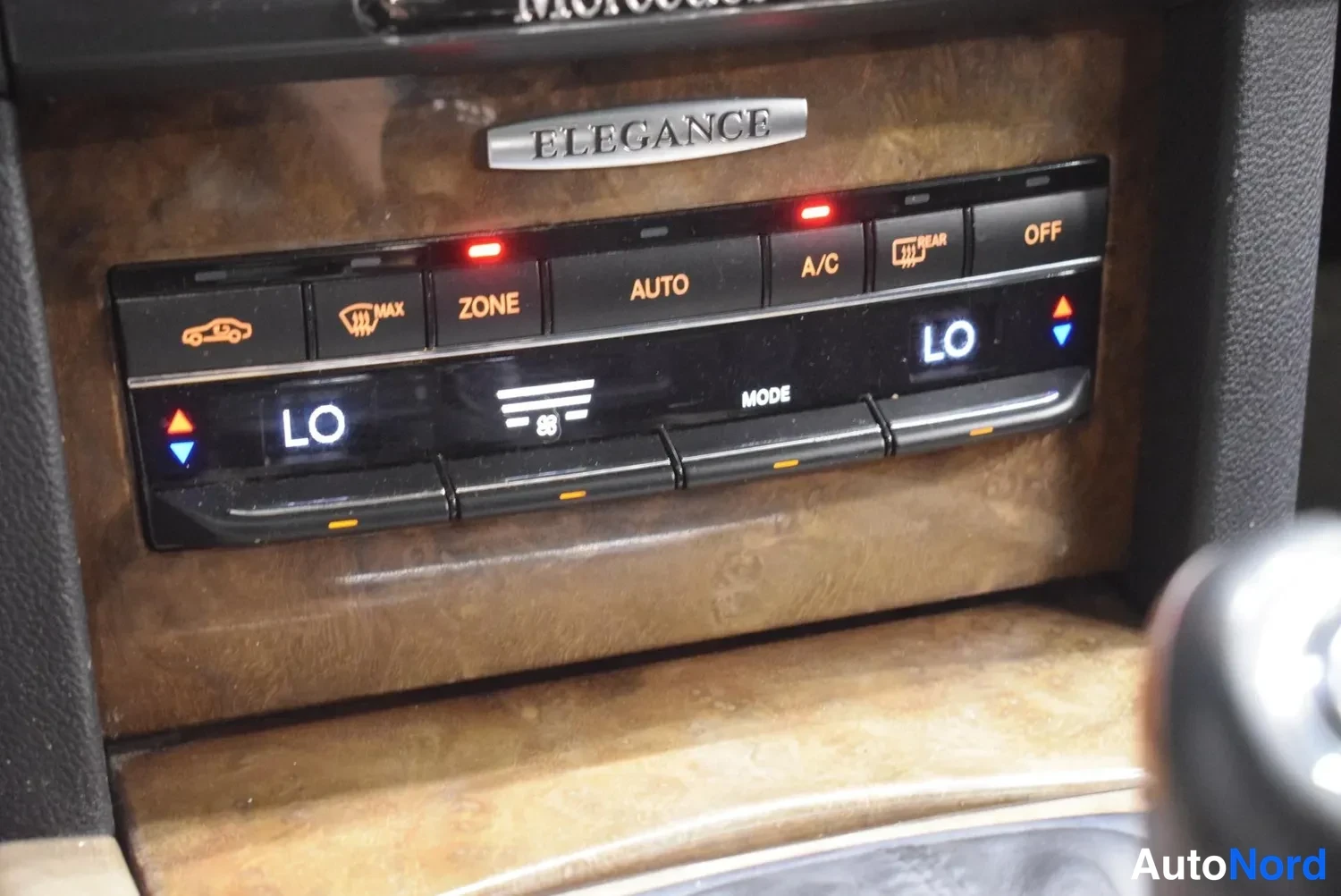 Yksityiskohta: Ilmastointilaitteen ohjauspaneeli lähikuva: AUTO-, ZONE- ja A/C-painikkeet, LO-näytöt ja ELEGANCE-koristenauha puolelinessä koristeosassa.