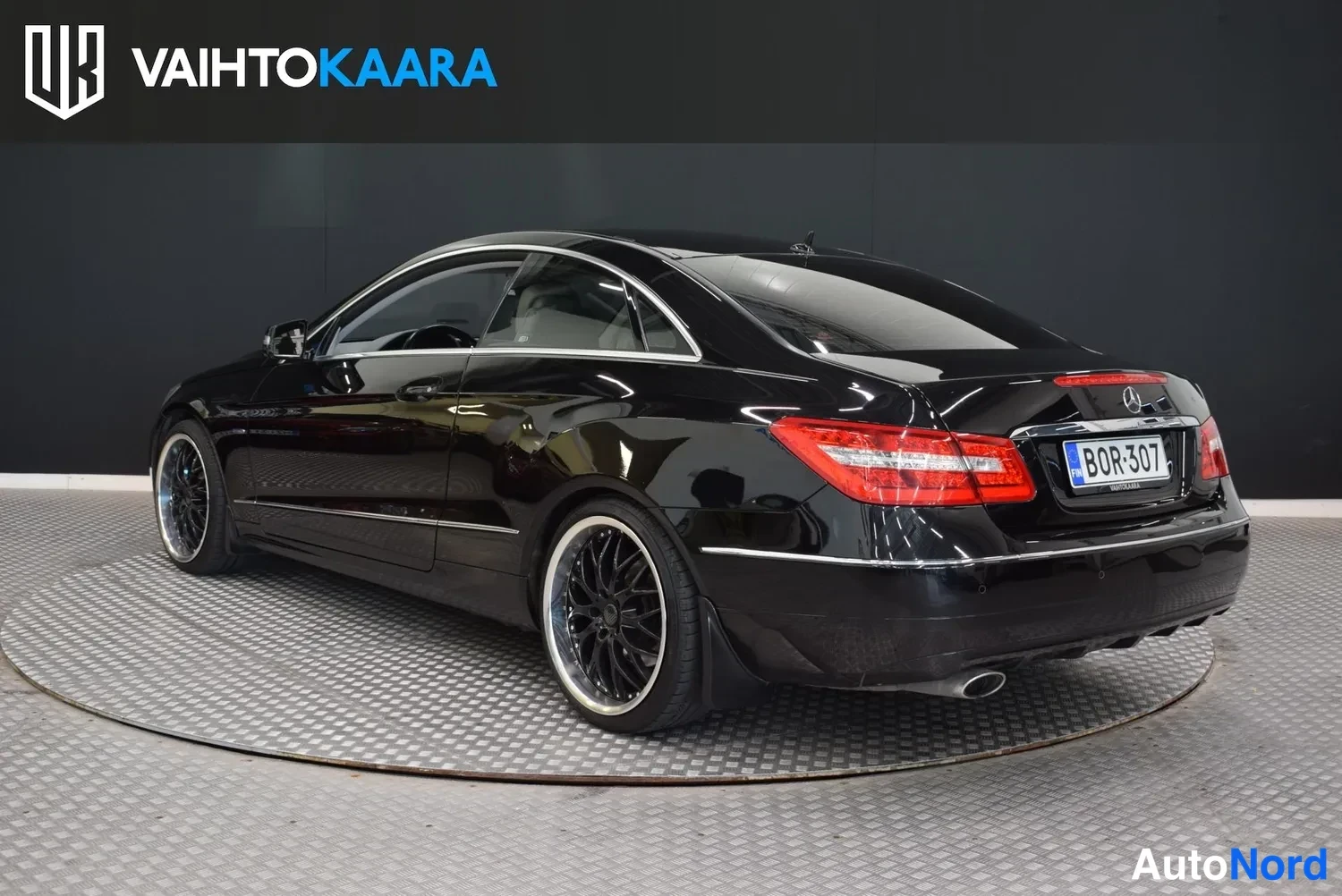 Takaviisto: Mustan Mercedes-Benz Coupén takaosan kolmioneljännesnäkymä takaa vasemmalle, punaiset takavalot ja rekisterikilpi.