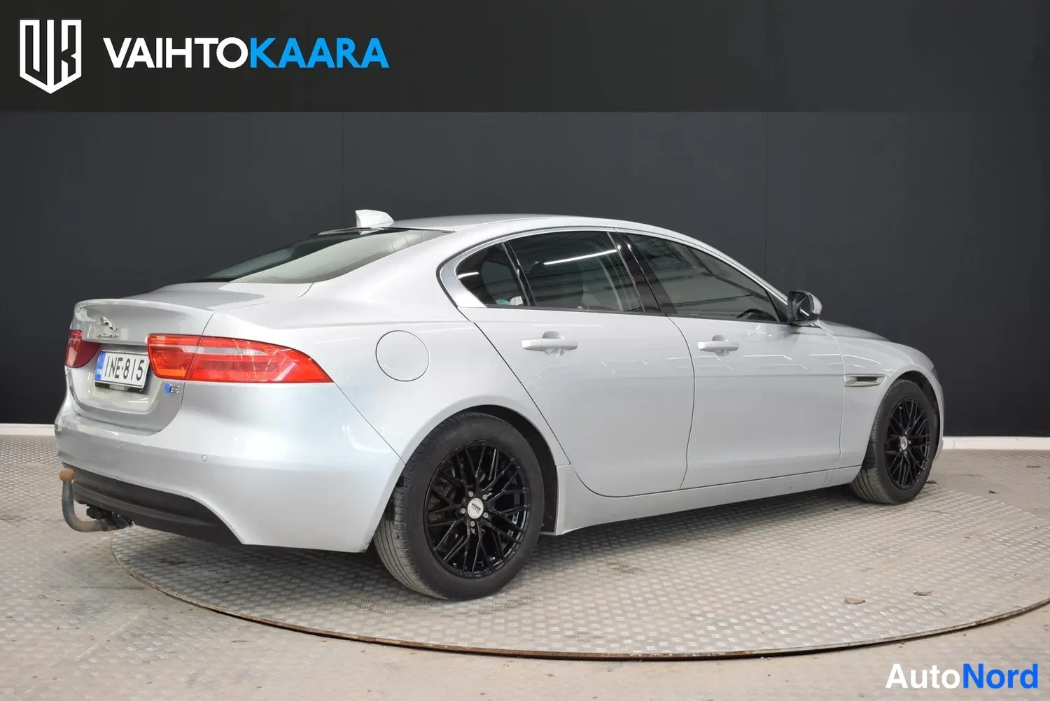 Takaviisto: Hopeanvärinen Jaguar XE -sedan takakulmanäkymä vasemmalta, punaiset takavalot ja rekisteritunnus.