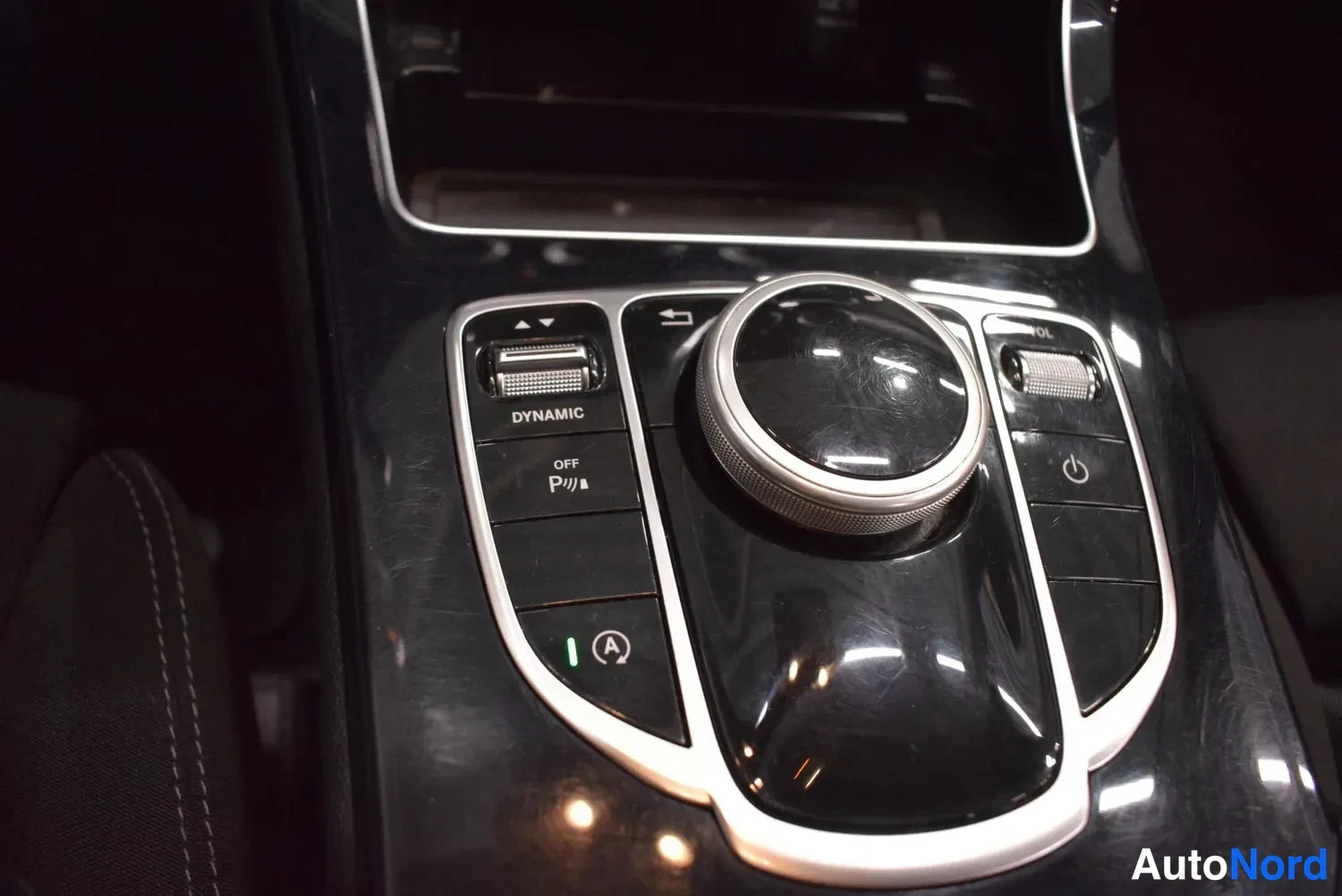 Muu: Sisäkuva: Mercedes-Benzin keskikonsolin DYNAMIC SELECT -ohjain ja COMAND-ohjaimisto, näkyvillä napit kuten DYNAMIC, P ja (A).