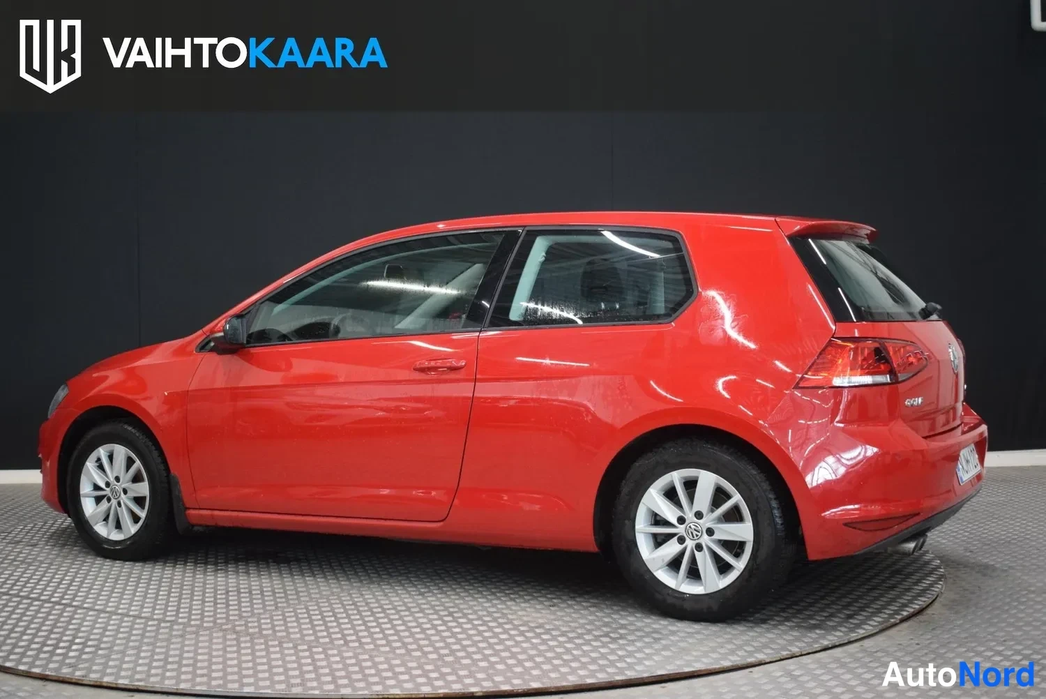 Takaviisto: Punainen Volkswagen Golf takaviistosta vasemmalta, takaosan ja kyljen näkyessä.