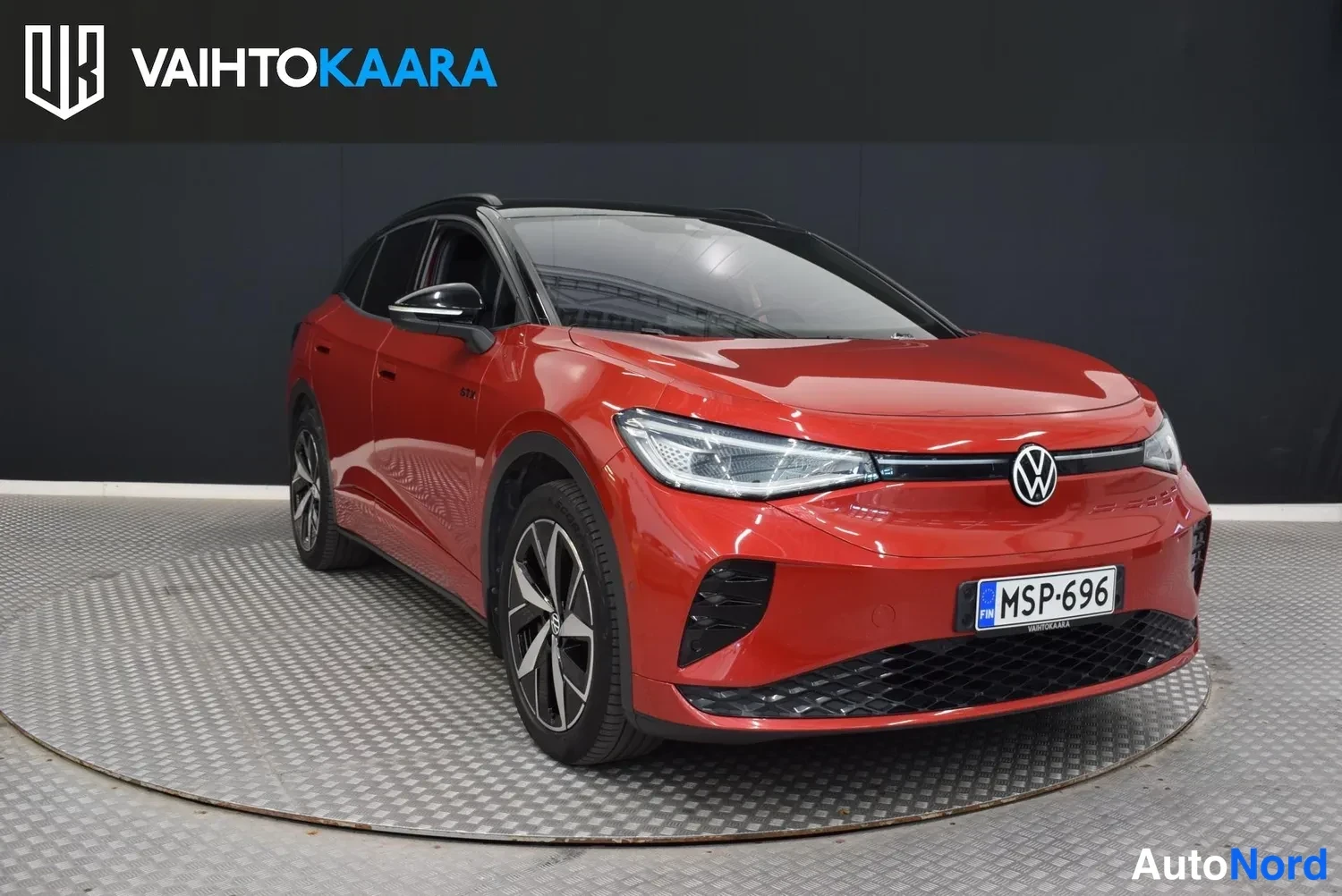 Etuviisto, nokka oikealle: Punaisen Volkswagen ID.4:n etukulma; keulakonna ja rekisterikilpi näkyvät, musta katto ja LED-ajovalot.