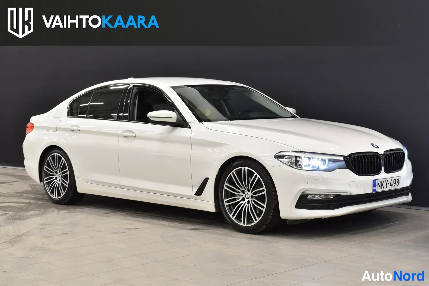 Etuviisto, nokka oikealle: BMW 520 sedan valkoisenä etuosa vasemmalle kääntynyt, rekisterikilpi, LED-etuvalot päällä.