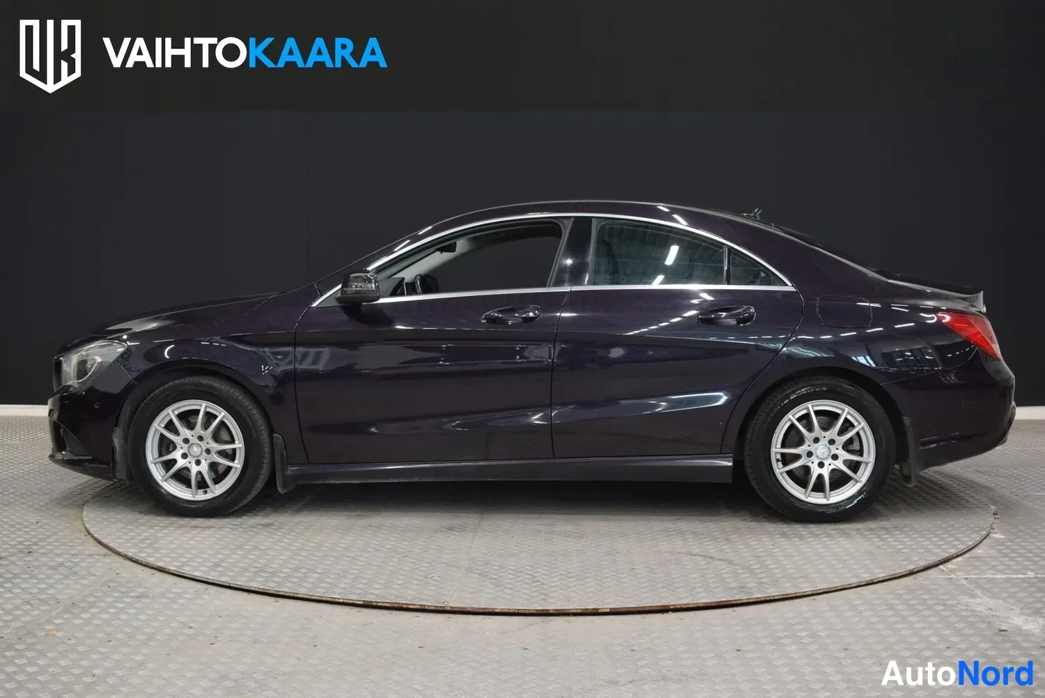 Sivulta: Tummanvioletti Mercedes-Benz CLA-näkymä sivulta vasemmalla studiovalaistuksessa