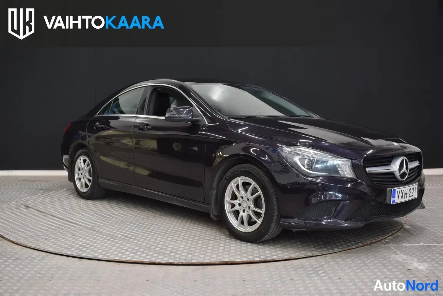 Etuviisto, nokka oikealle: Etukolmasosakuva tummanvioletista Mercedes-Benz CLA -sedanista, etusäleikkö ja rekisterikilpi näkyvät.