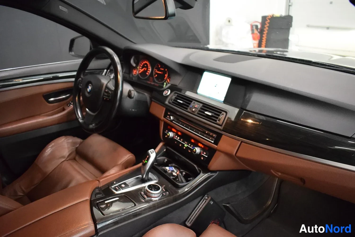 Muu: Auton sisätilat: BMW-ohjauspyörä, kojelauta, keskikonsolilla automaattivaihteen valitsin, infotainment-näyttö ja ruskeat nahkapenkit.