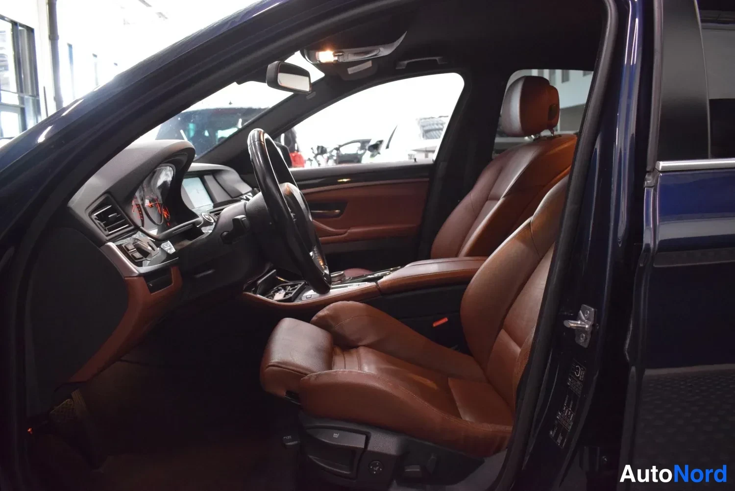 Muu: BMW:n etusseat ruskeahkossa nahkaverhoilussa kuljettajan oven ollessa auki.