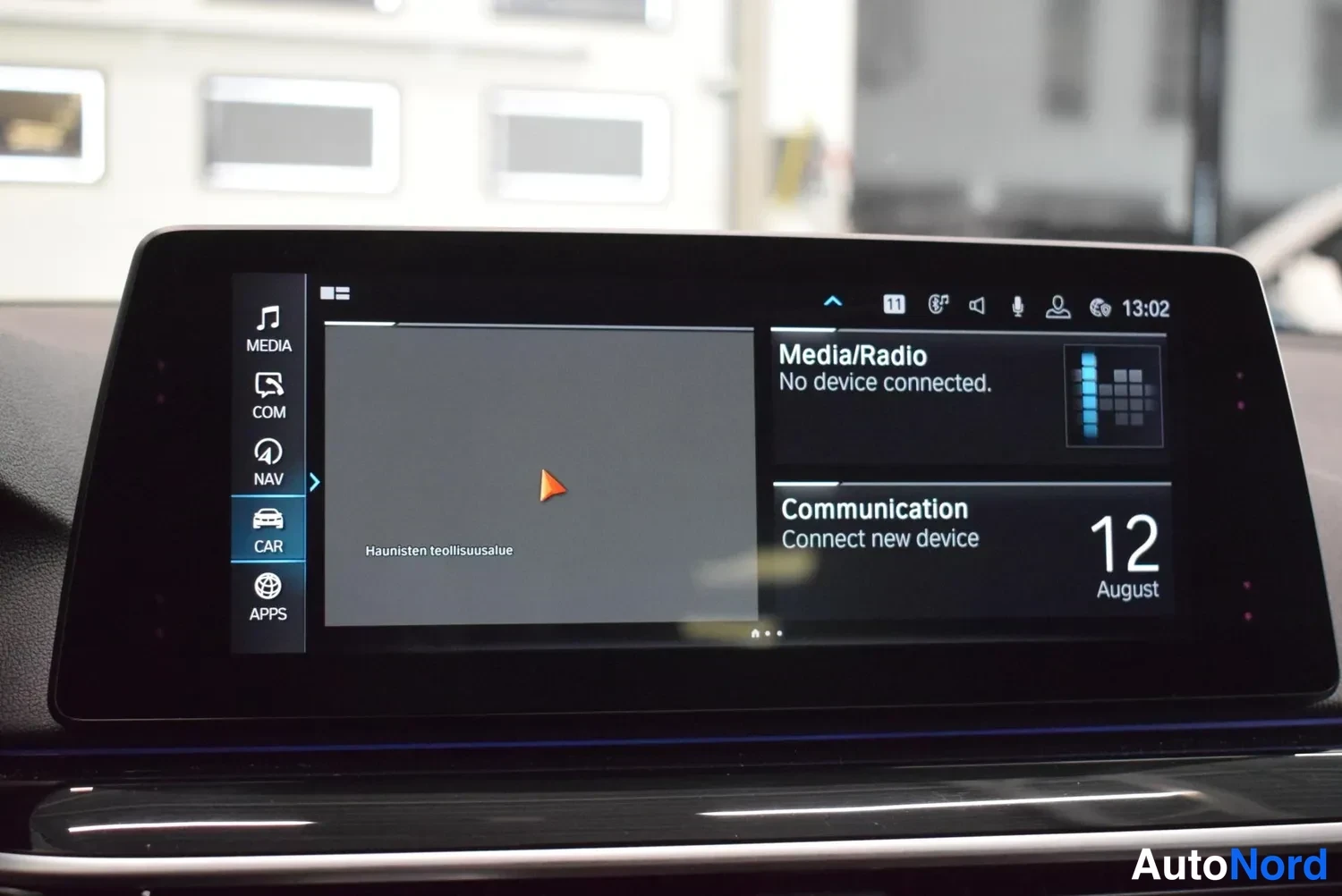 Yksityiskohta: Keskirivin infotainment-näyttö, jossa valikot MEDIA, COM, NAV, CAR ja APPS.