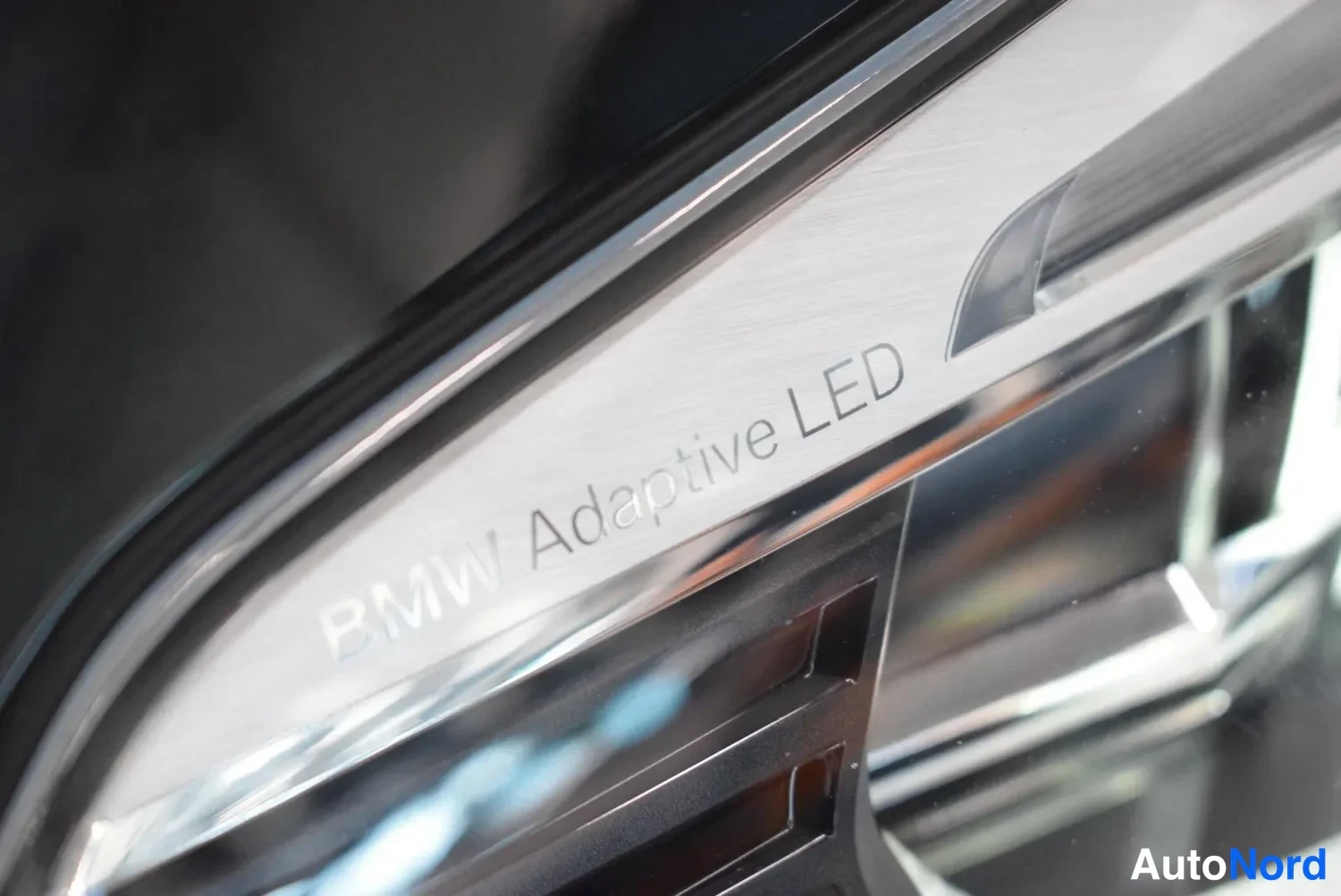 Muu: lähikuva ajoneuvon etutakavaloa, jossa lukee teksti BMW Adaptive LED.