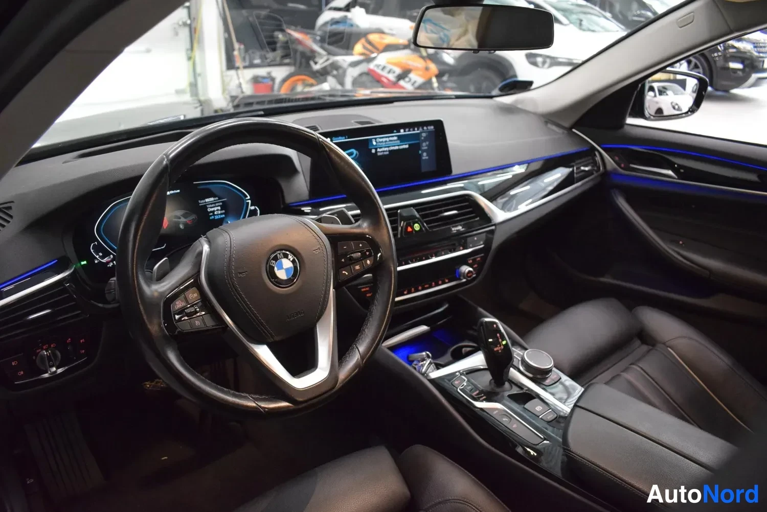 Muu: Ohjaamosta näkyy BMW-merkitty ohjauspyörä, mediaruutu, keskikonsoli ja vaihdevipu.