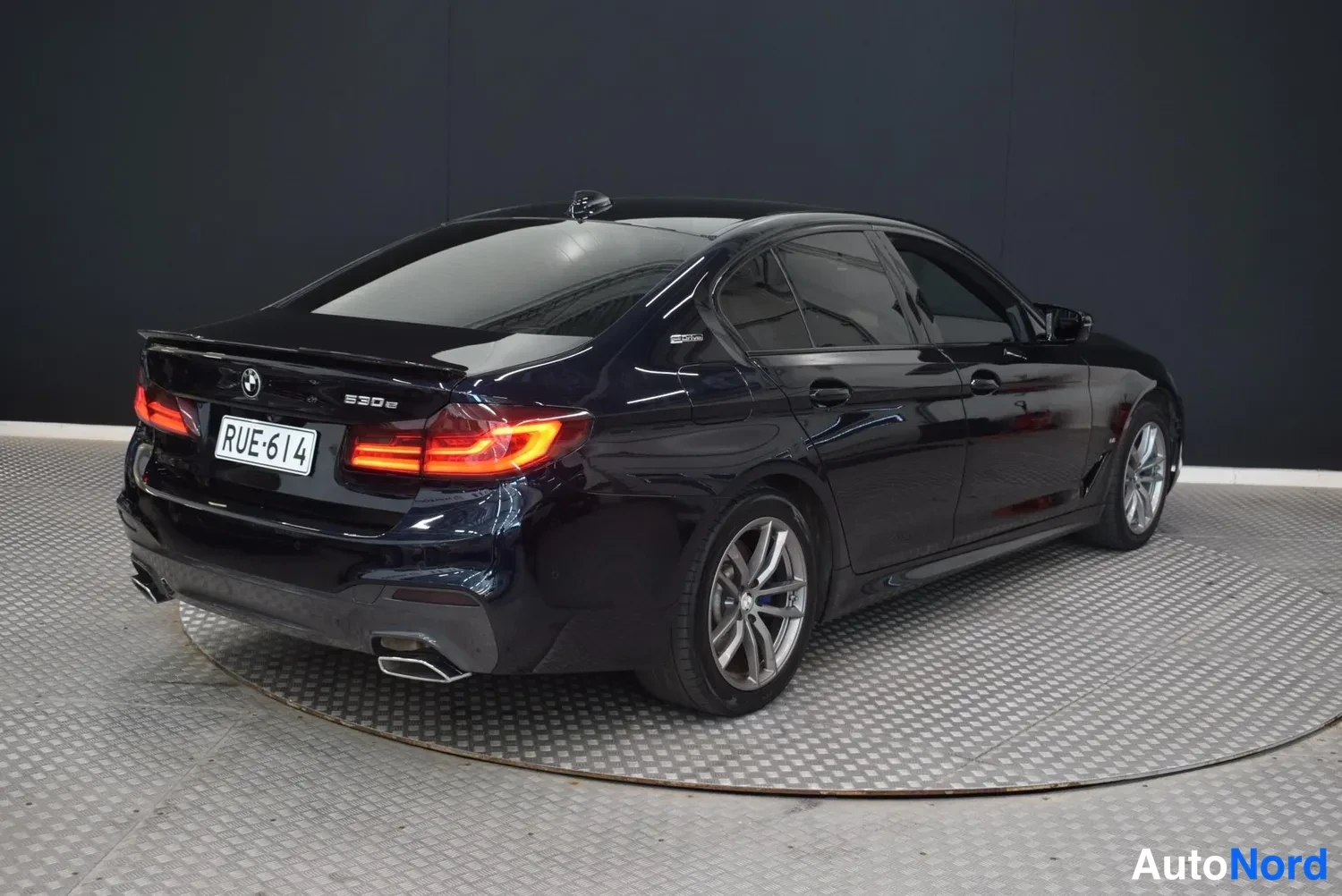 Takaviisto: Sinimustan BMW-sedan takaosa oikealta kolmivinkkaisesti, takavaloissa punainen valo.