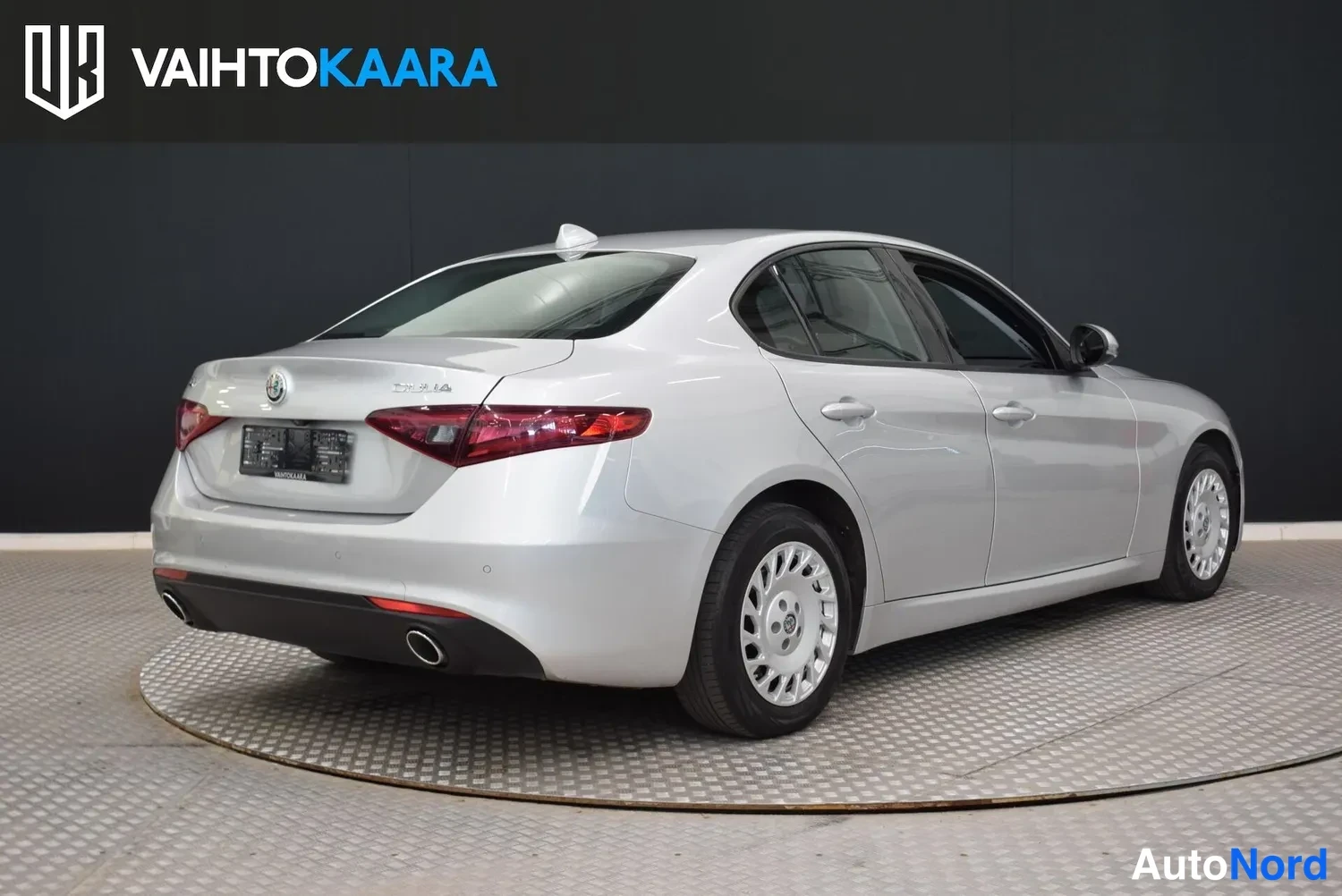 Takaviisto: Hopeanharmaa Alfa Romeo Giulia -sedan takanurkka oikealta, takavalot ja kori näkyvissä.