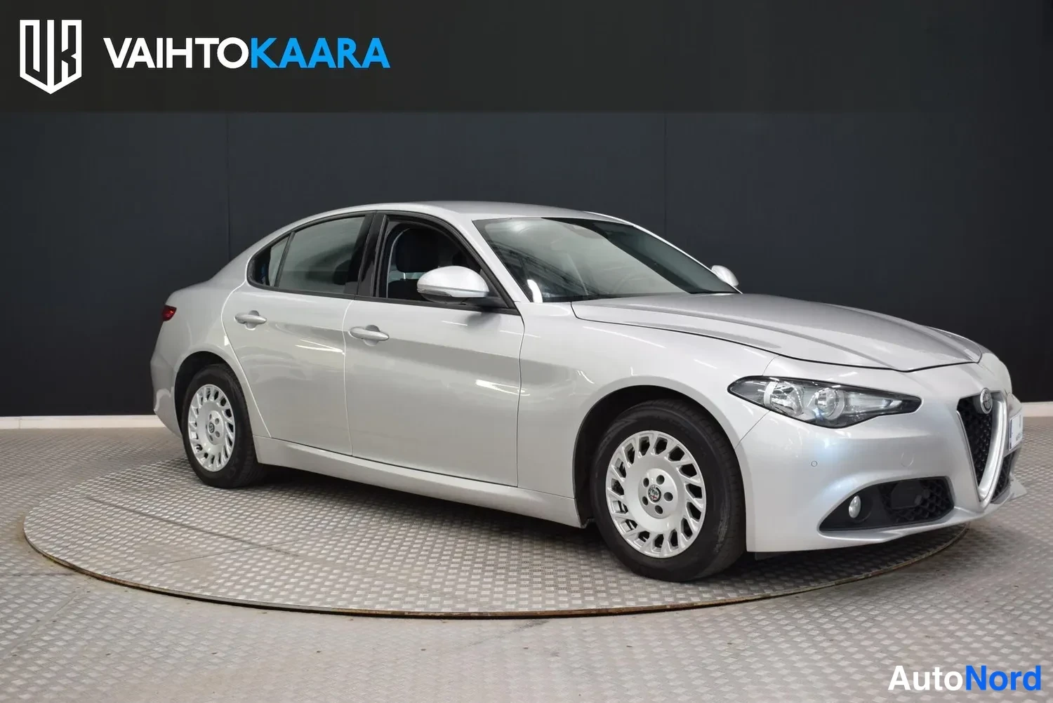 Etuviisto, nokka oikealle: Hopeanvärinen Alfa Romeo Giulia kolmioneljäsosakuvaussa etupuoli ja vasen kylki näkyvissä.