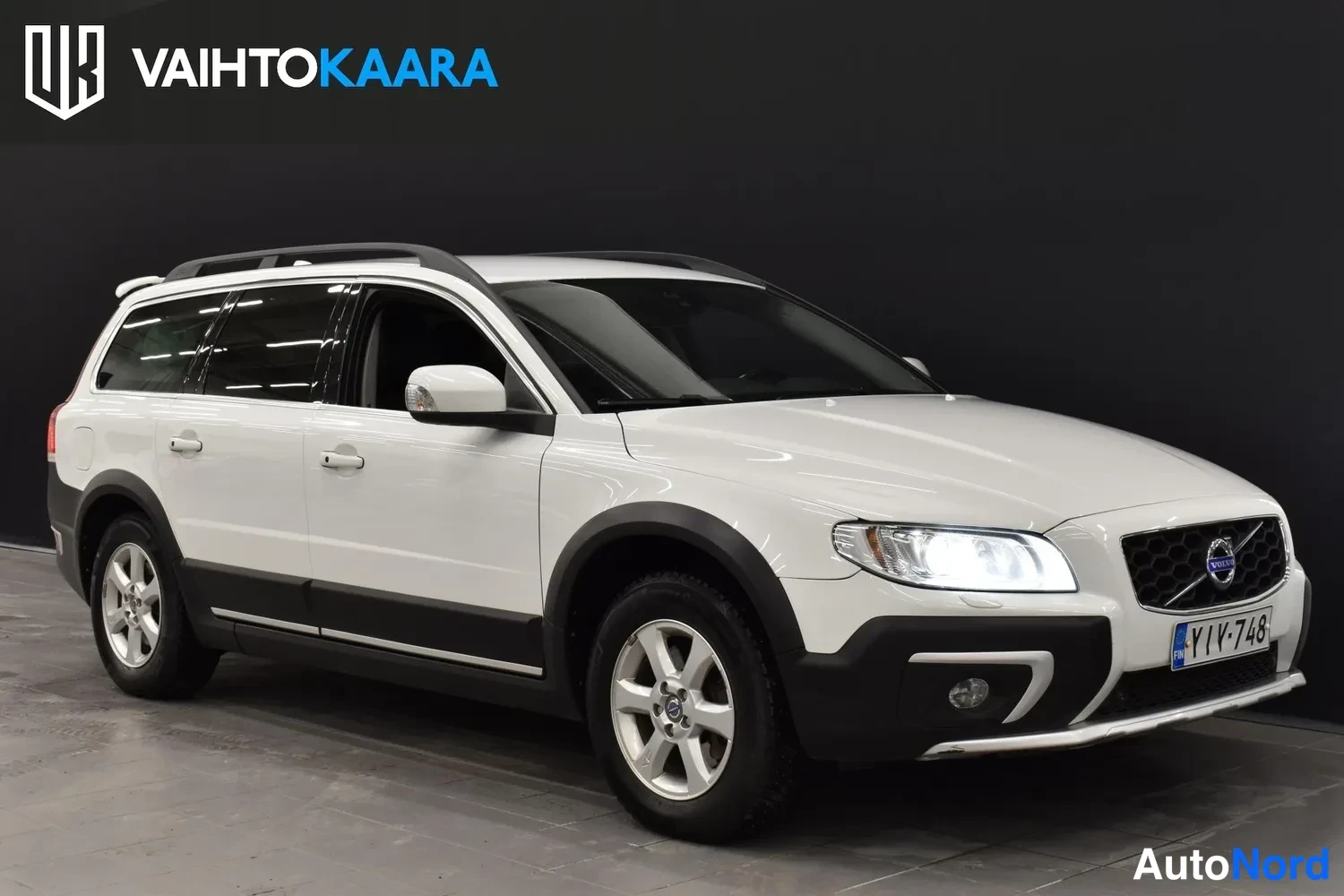 Etuviisto, nokka oikealle: Volvo XC70 etuviistöstä oikealta kuvattuna; valkoinen kori, sumuvalot ja etupuskurin kromilista näkyvät.