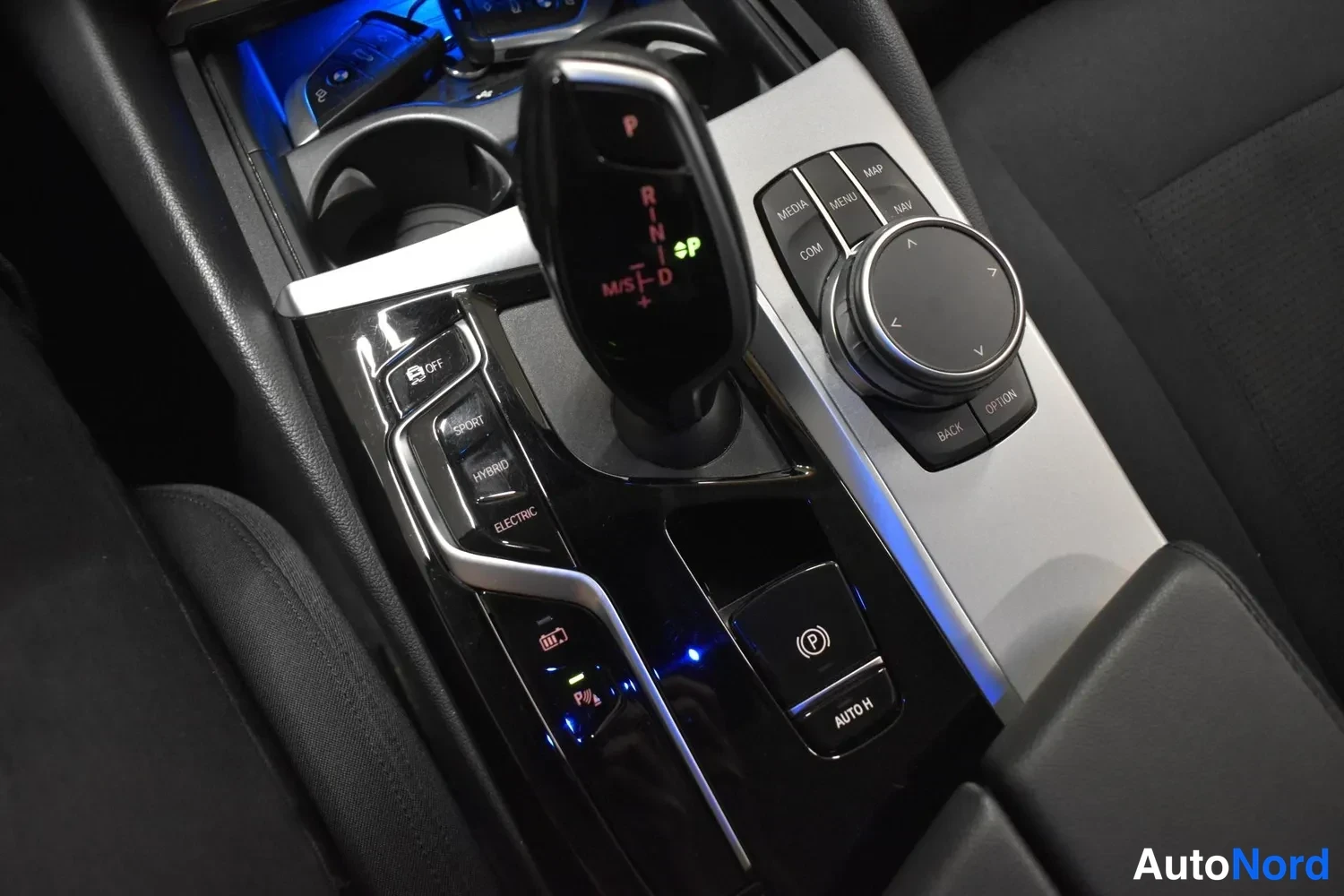 Yksityiskohta: Automaattivaihteenvalitsin ja iDrive-ohjain keskitunnelissa, hybridin SPI/HYBRID/ELECTRIC-painikkeet.