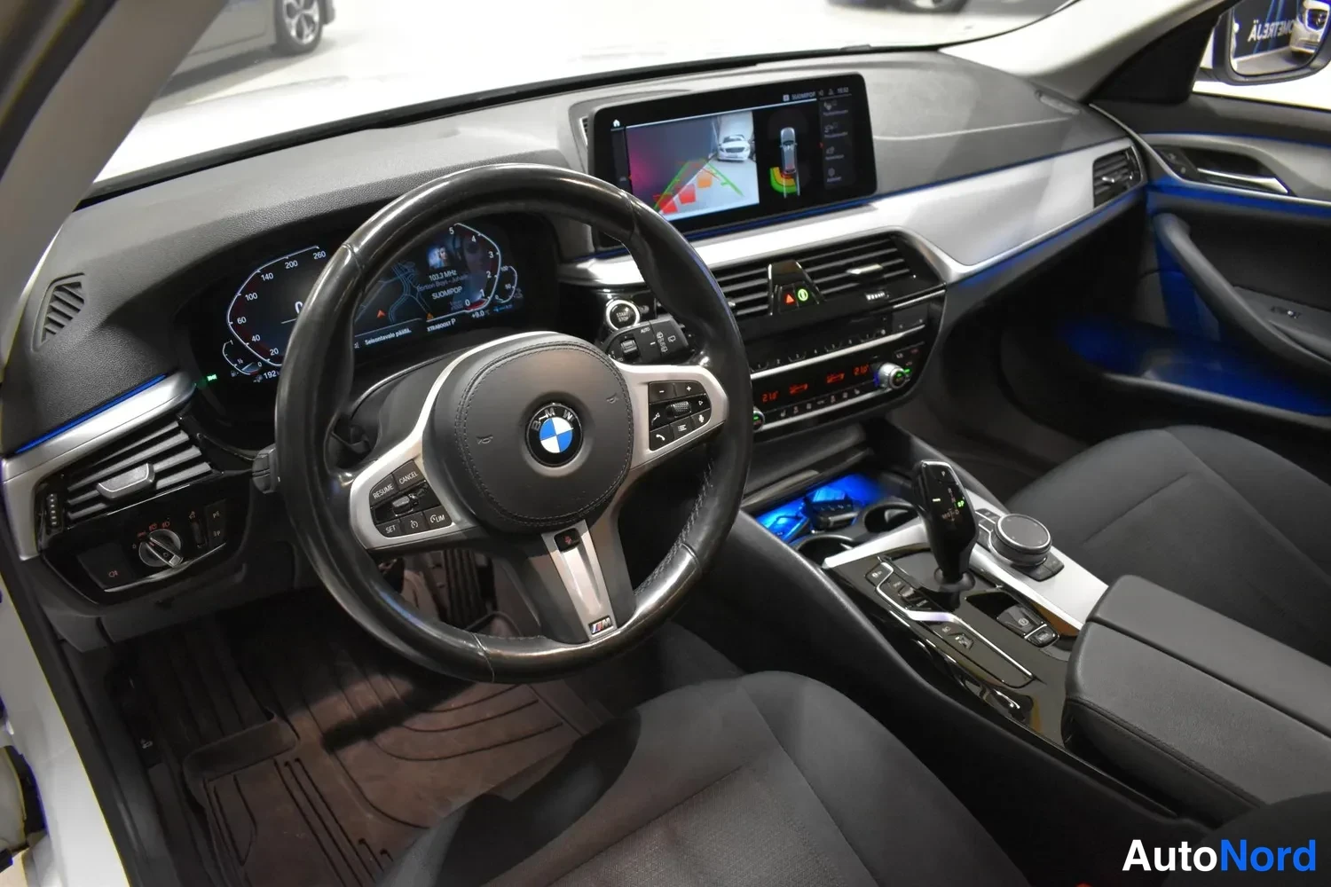 Muu: Kuljettajan näkökulma ohjaamosta: BMW-ohjauspyörä, digitaalinen mittaristo ja tauluton infotainment-näyttö.