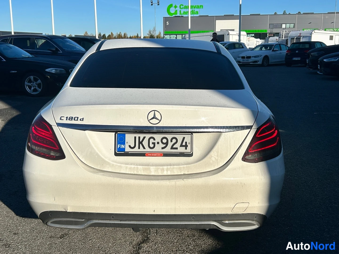 Takaa: Valkoisen Mercedes-Benz C-sarjan sedan takapää suoraan takaa, takana C 180 d -merkintä ja rekisteritunnus.