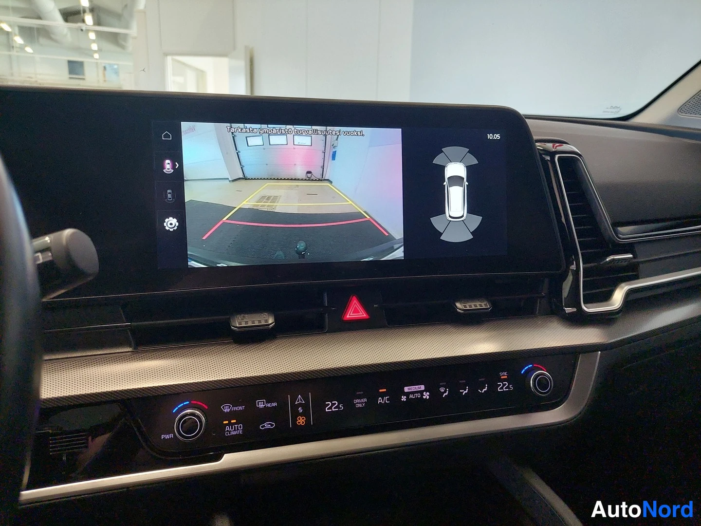 Muu: Kojetaulun näyttö näyttää peruutuskamerakuvan ja 360 asteen ajoneuvonäkymän, alla ilmastointipaneeli.