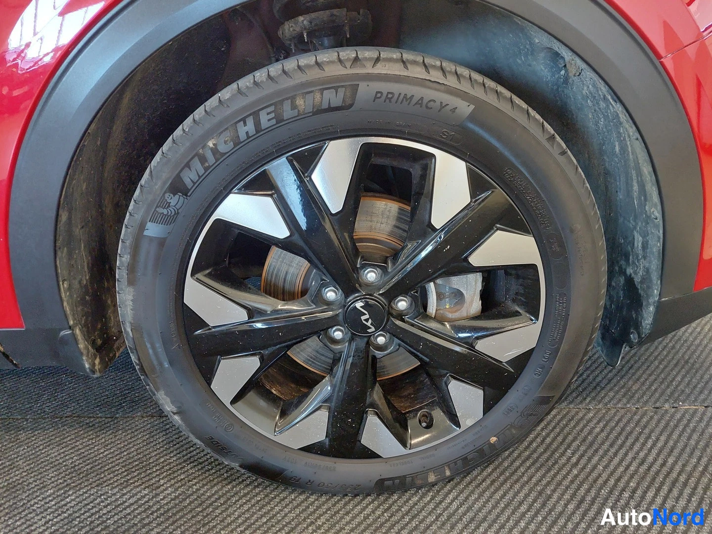 Muu: Punaisen auton pyöränläheinen: musta Metallivärikehys ja hopeapinnat, Michelin Primacy 4 -rengas, jarrulevy ja Kia-merkillinen napakeskus