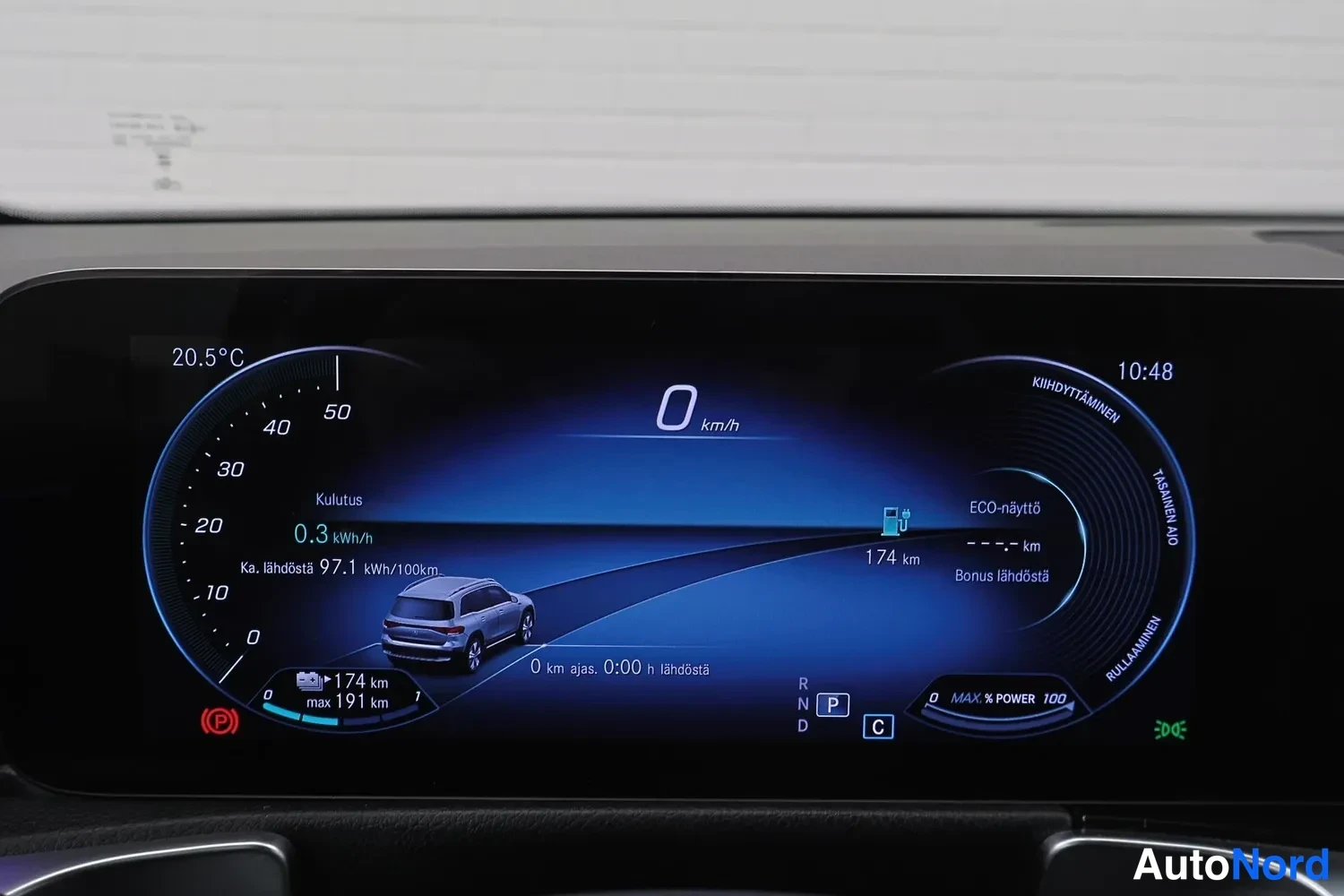Yksityiskohta: Digitaalinen mittaristo kuvattuna suoraan edestä: nopeus 0 km/h, kulutus 0,3 kWh/h, ka. lähdöstä 97,1 kWh/100km, vaihteisto P, ulkolämpötila 20,5 °C ja kello 10