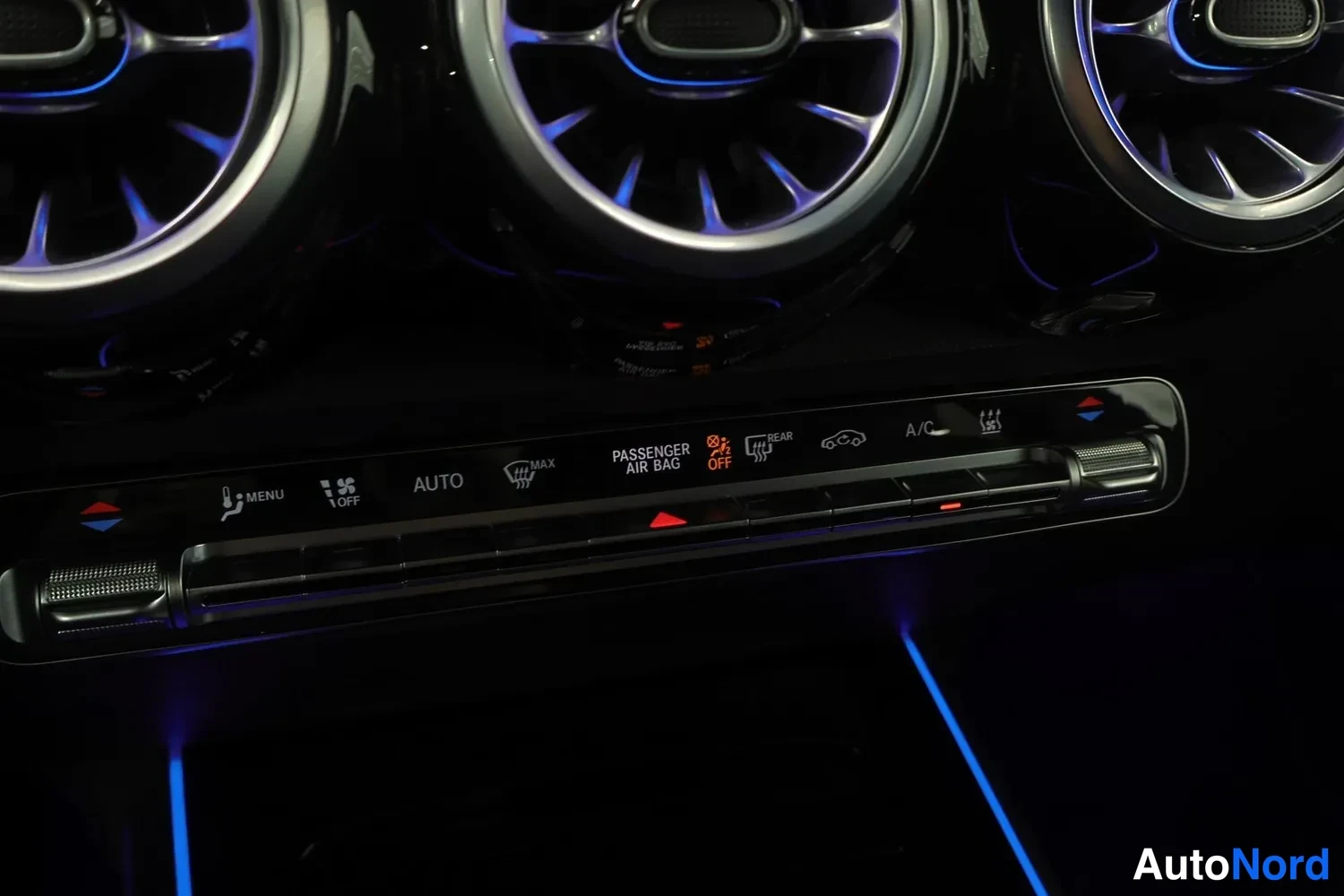 Muu: Keskikonsolin ilmastointilaitteen painikkeet merkinnöillä AUTO, A/C ja MAX, suuttimet sinisellä korostusvalaistuksella.