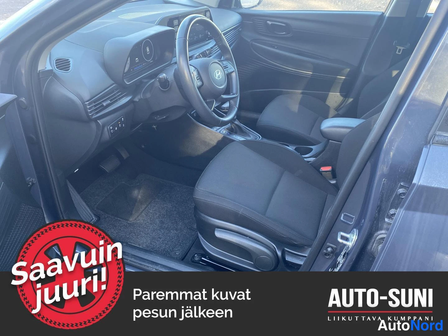 Muu: Hyundai i20:n etusisätila ohjaamosta kuvattuna: ratin ja kojetaulun näkymä, mustat kankaanverhoillut etuistuimet ja keskikonsoli.