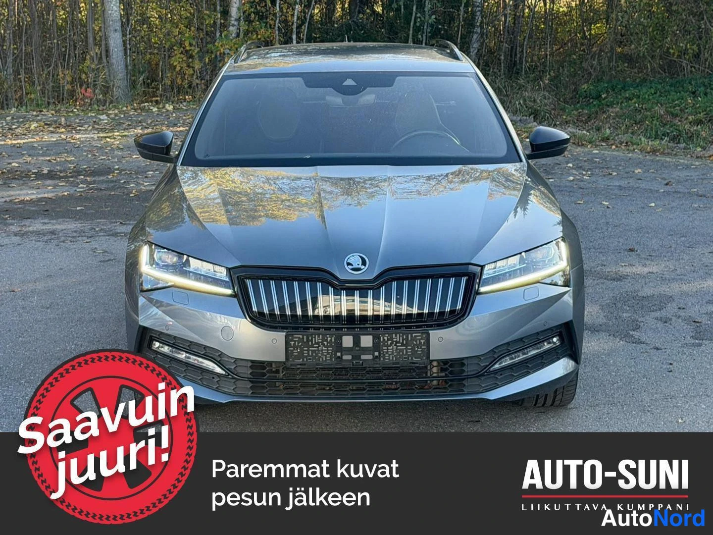 Edestä: Skoda Superb -farmari edestä päin, harmaa kori ja LED-ajovalot päällä.