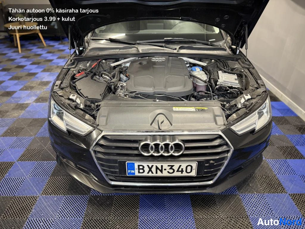 Edestä: Mustan Audi-hatchbackin konepelti on auki ja moottoritila näkyy; etusäleikkö ja rekisteri ovat näkyvissä.