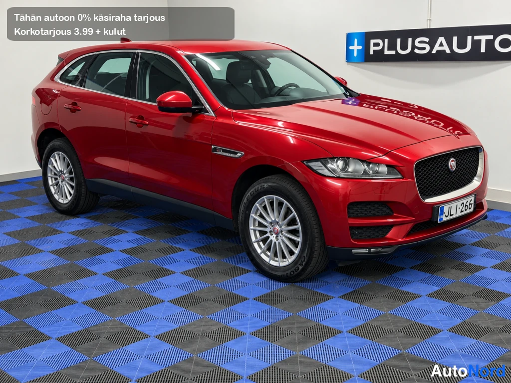 Etuviisto, nokka oikealle: Punainen farmariauto etuokolokuvassa autosalon sinimustaruutollisella lattialla.