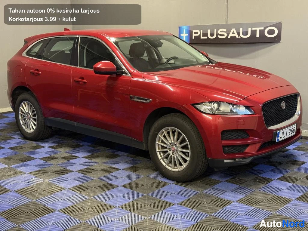 Etuviisto, nokka oikealle: Punainen farmariauto etuokolokuvassa autosalon sinimustaruutollisella lattialla.