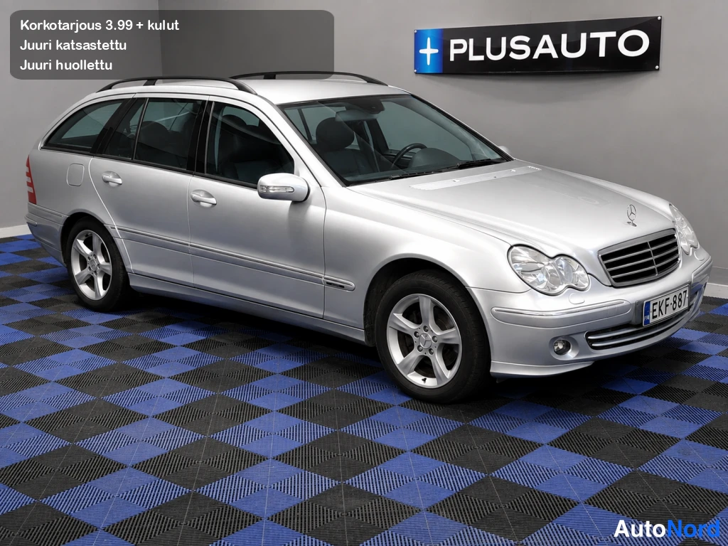 Etuviisto, nokka oikealle: Hopeinen Mercedes-Benz C 180 Kompressor -farmari etuokolänäkymästä, rekisterikilpi, kattokaiteet ja viisipuolaiset alumiinivanteet näkyvissä.
