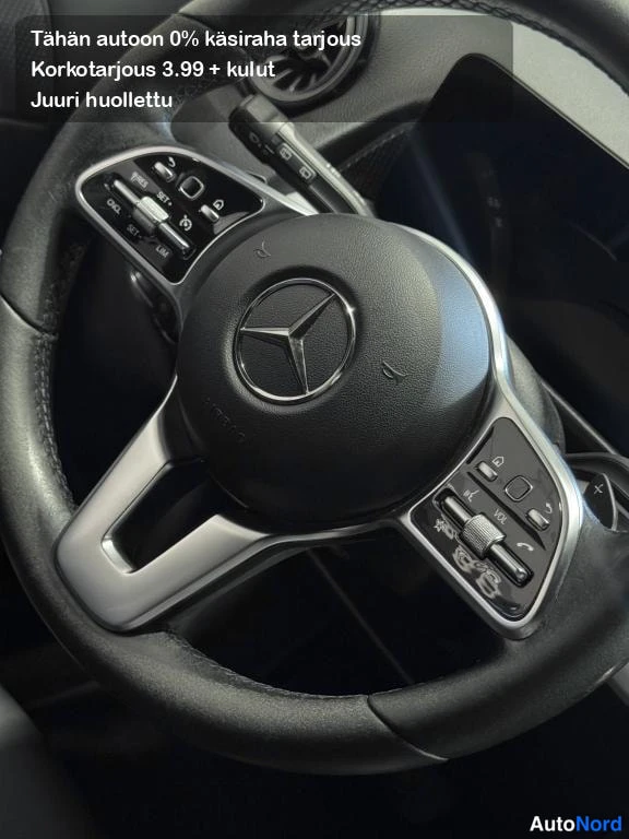 Muu: Mercedes-Benzin ohjauspyörän lähikuva, keskellä tähtimerkki ja monitoimipainikkeet molemmilla pubeilla.