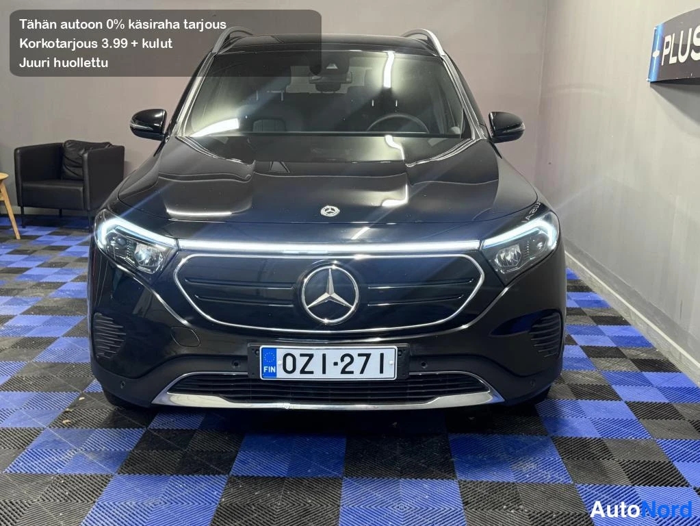 Edestä: Mercedes-Benz EQB:n suora etunäkymä, musta kori, täys-LED-ajovalot päällä, Mercedes-tähti etusäleikössä, rekisteri.