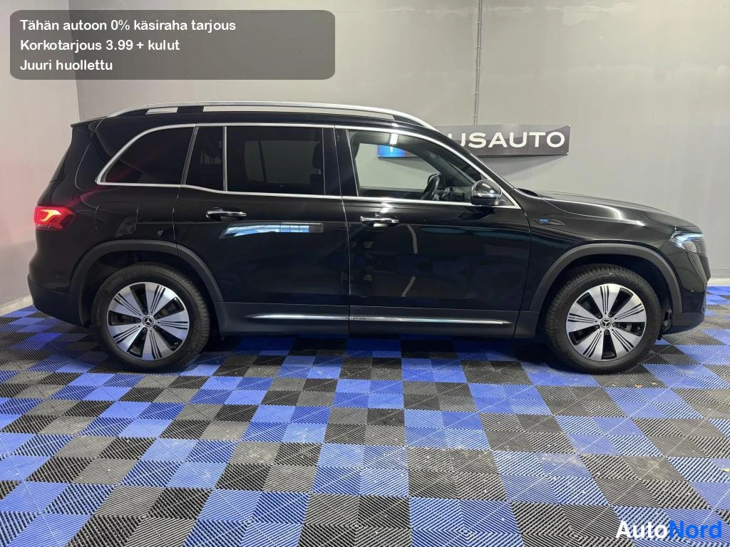 Sivulta: Musta Mercedes-Benz EQB -maasturin sivuprofiili sisätiloissa sinimustalla ruutulattialla.