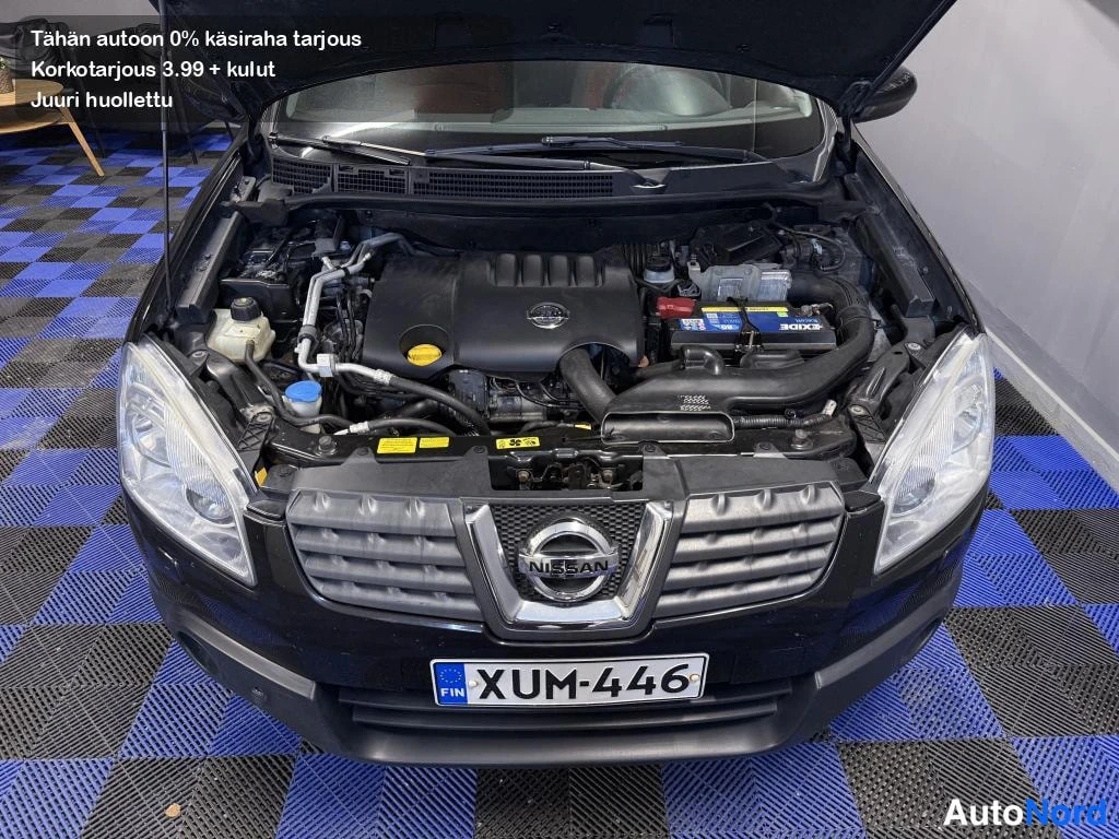 Edestä: Auton konepelti auki: moottoritila näkyvillä, keulassa Nissan-merkitty etusäleikkö ja rekisterikilpi.