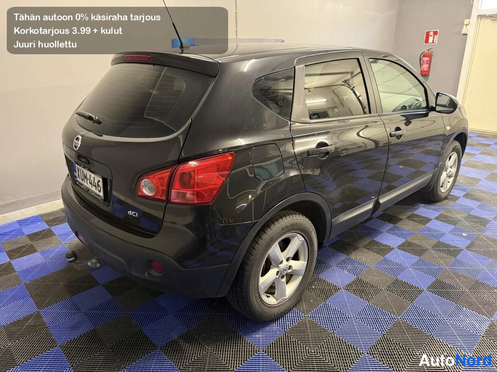 Takaviisto: Mustan Nissan Qashqain takaosa ja vasen kylki kuvattuna kolmen neljäsosan kulmasta sisätiloissa sinimustassa ruutulattiaossa; rekisterikilpi, dCi-merkintä ja ve