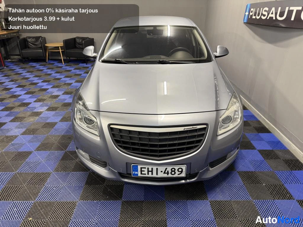 Edestä: Hopeanharmaan sedanin etupää suoraan edestä kuvattuna; rekisterikilpi, Opel-merkitty etusäleikkö ja sumuvalot erottuvat.