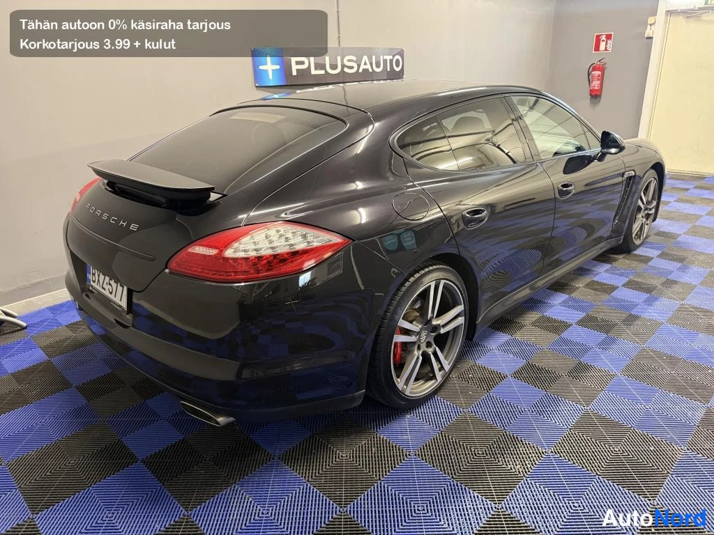 Takaviisto: Mustan Porsche Panameran takakolmannesvasen näkymä, päälle nostettu takasiipi ja punaiset takavalot.
