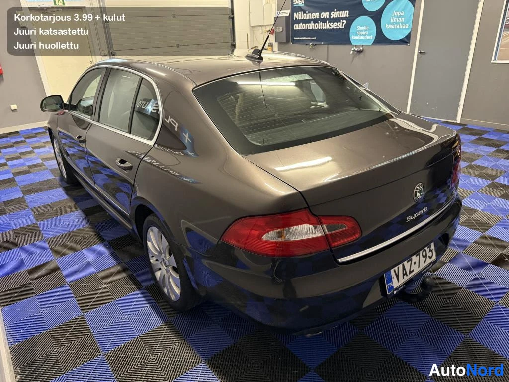 Takaviisto: Auton takaosa ja kylki takaviistosta yläkulmasta; tummanruskea koripelti, takavalot, Skoda-merkki ja rekisterikilpi.